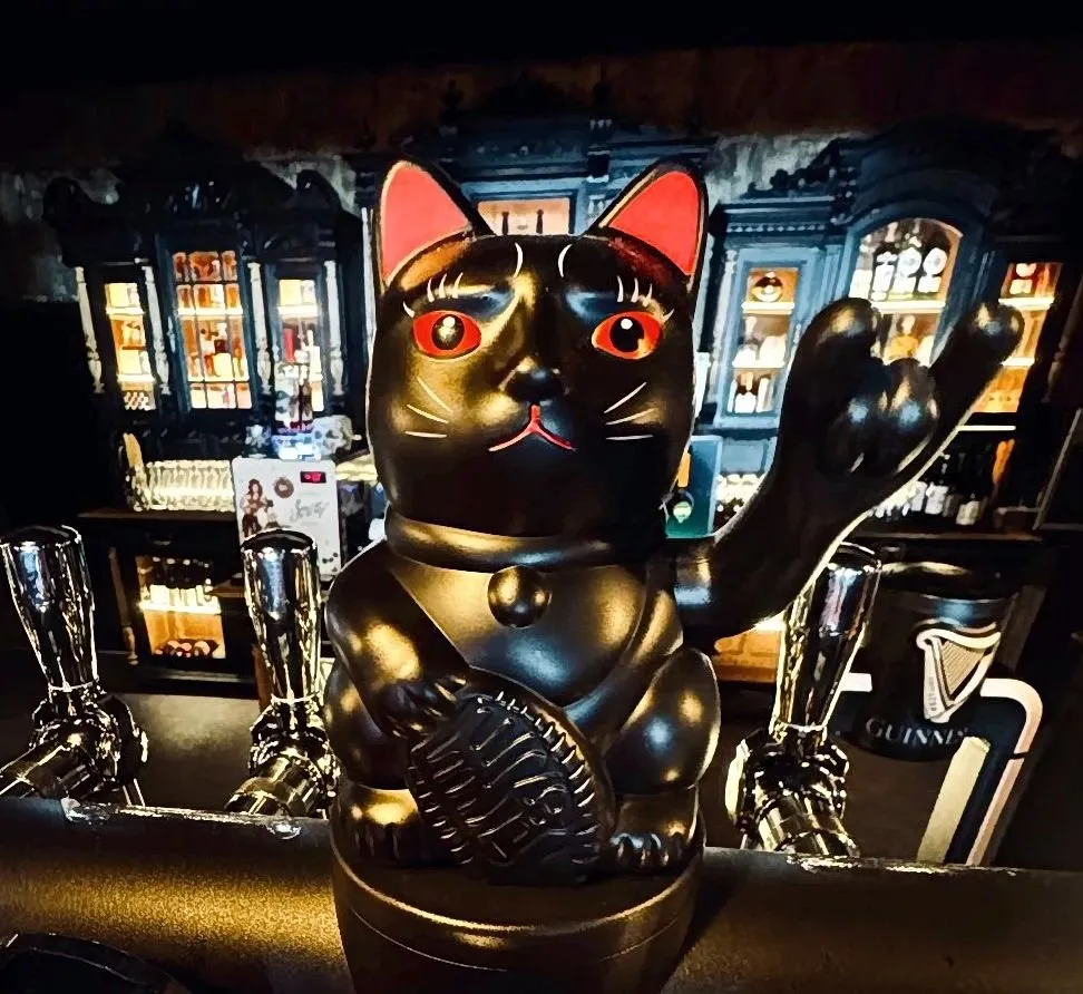 Un chat porte-bonheur noir sur le comptoir du bar
