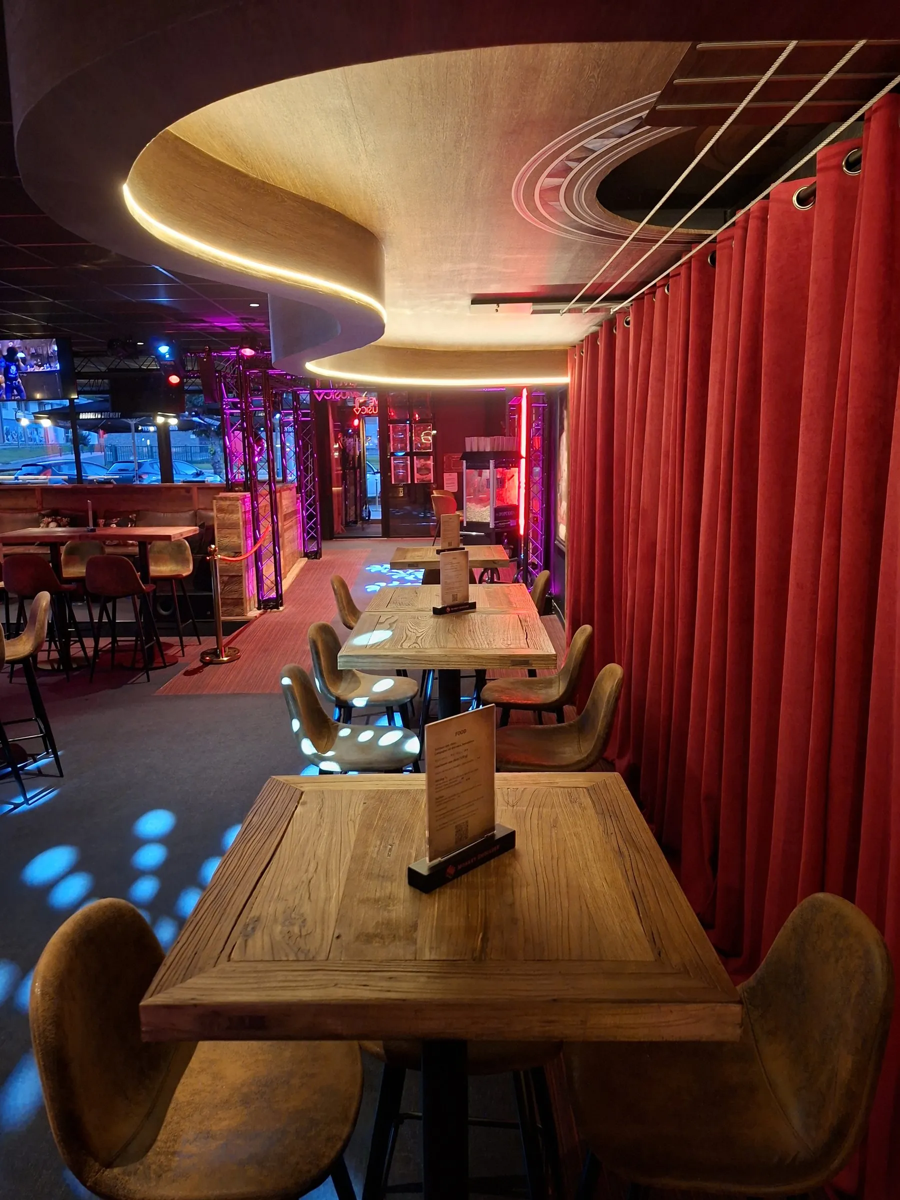 Un coin de tables en bois le long d'un rideau de velours rouge