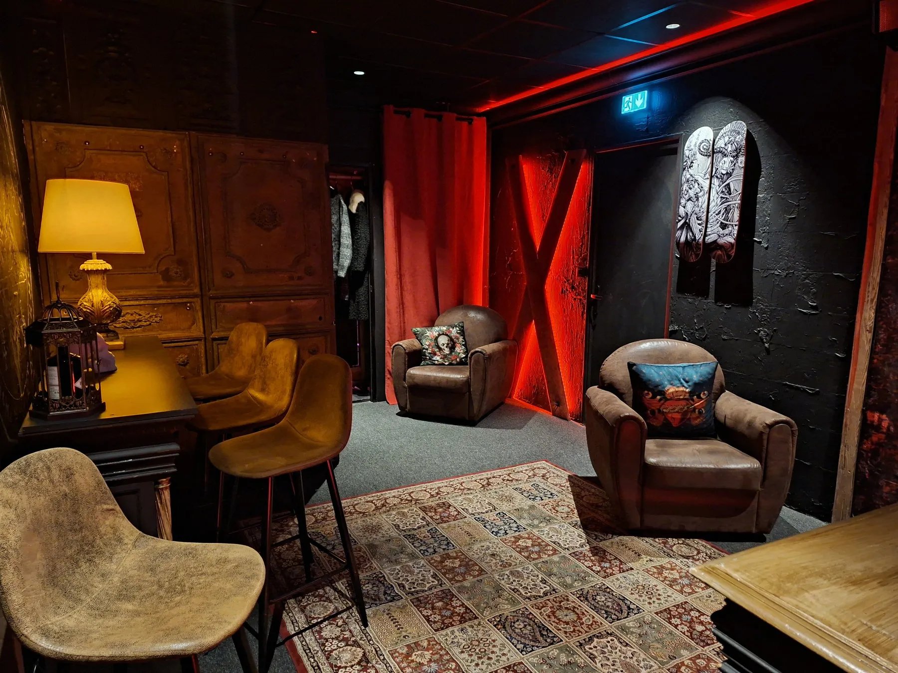 Le salon de la salle de karaoké : fauteuils club en cuir, lampe et porte rouge