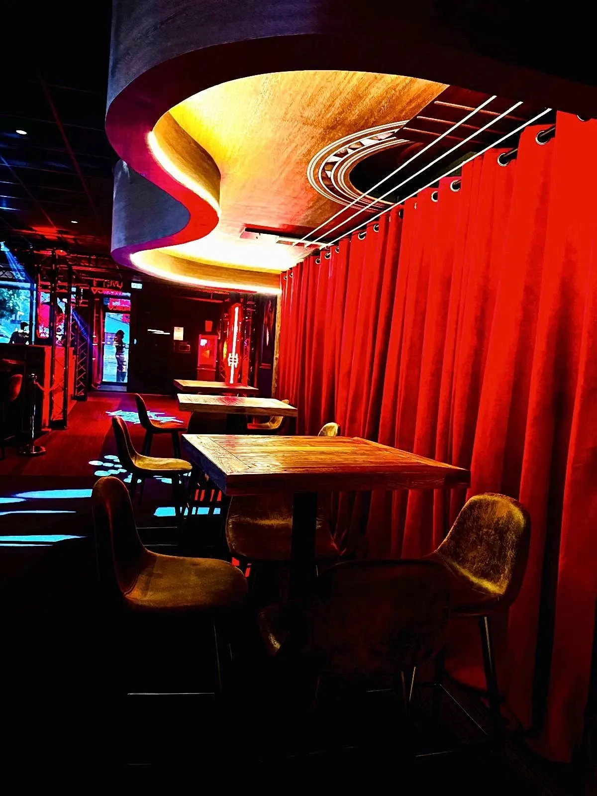 Tables nichées sous un plafond courbe, rideau de velours rouge