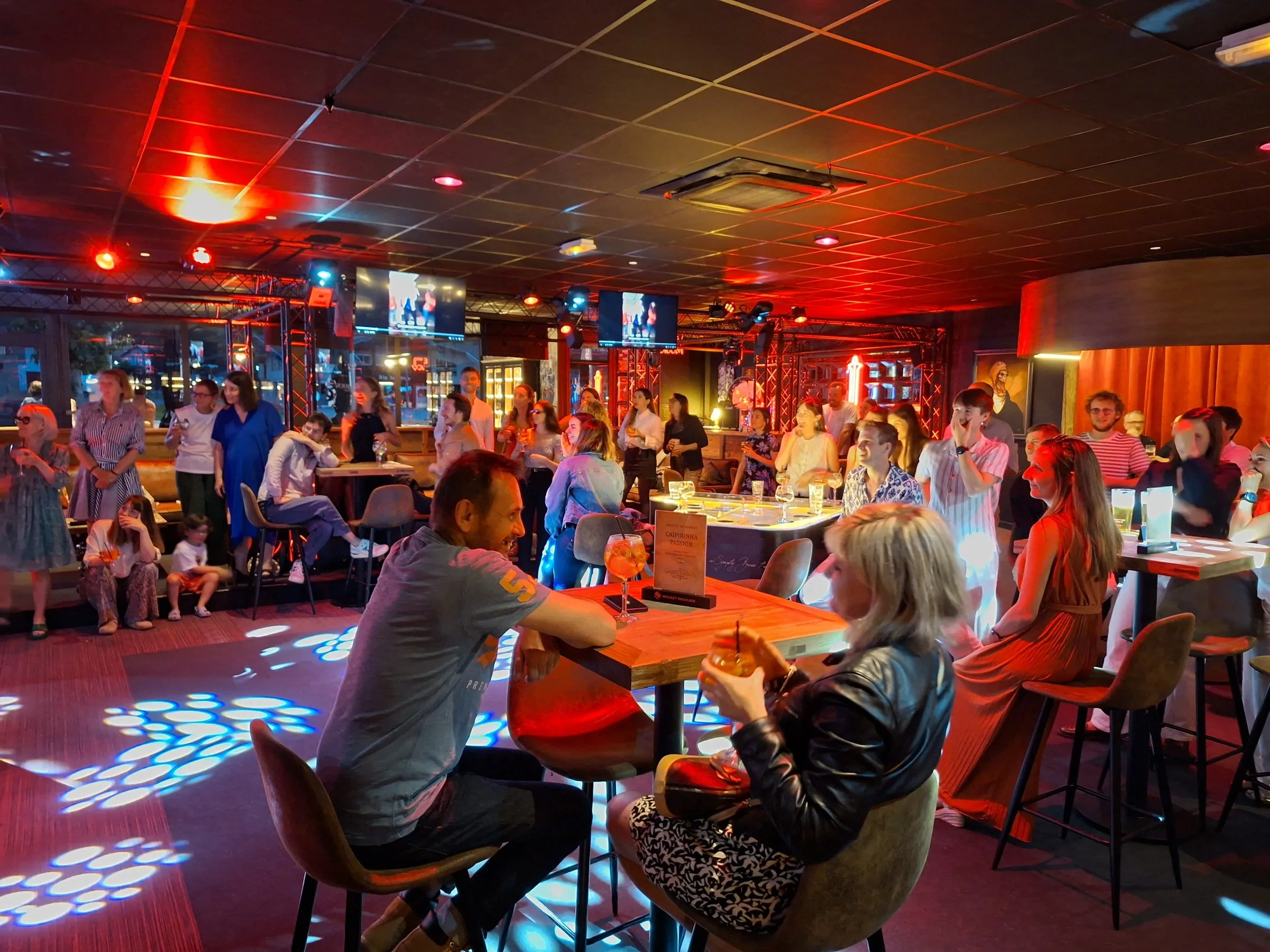 La salle du Saint Rock Bar pleine un soir de fête, sous les lumières rouges